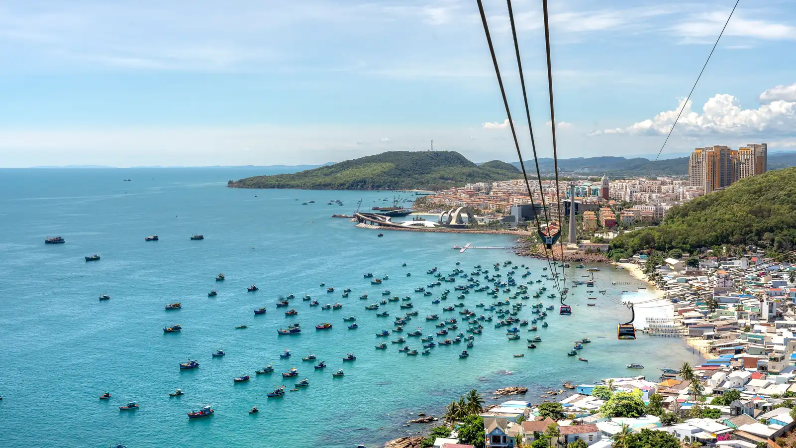 A breathtaking aerial view of Phu Quoc Island with boats, coastline, and cable car over blue water.