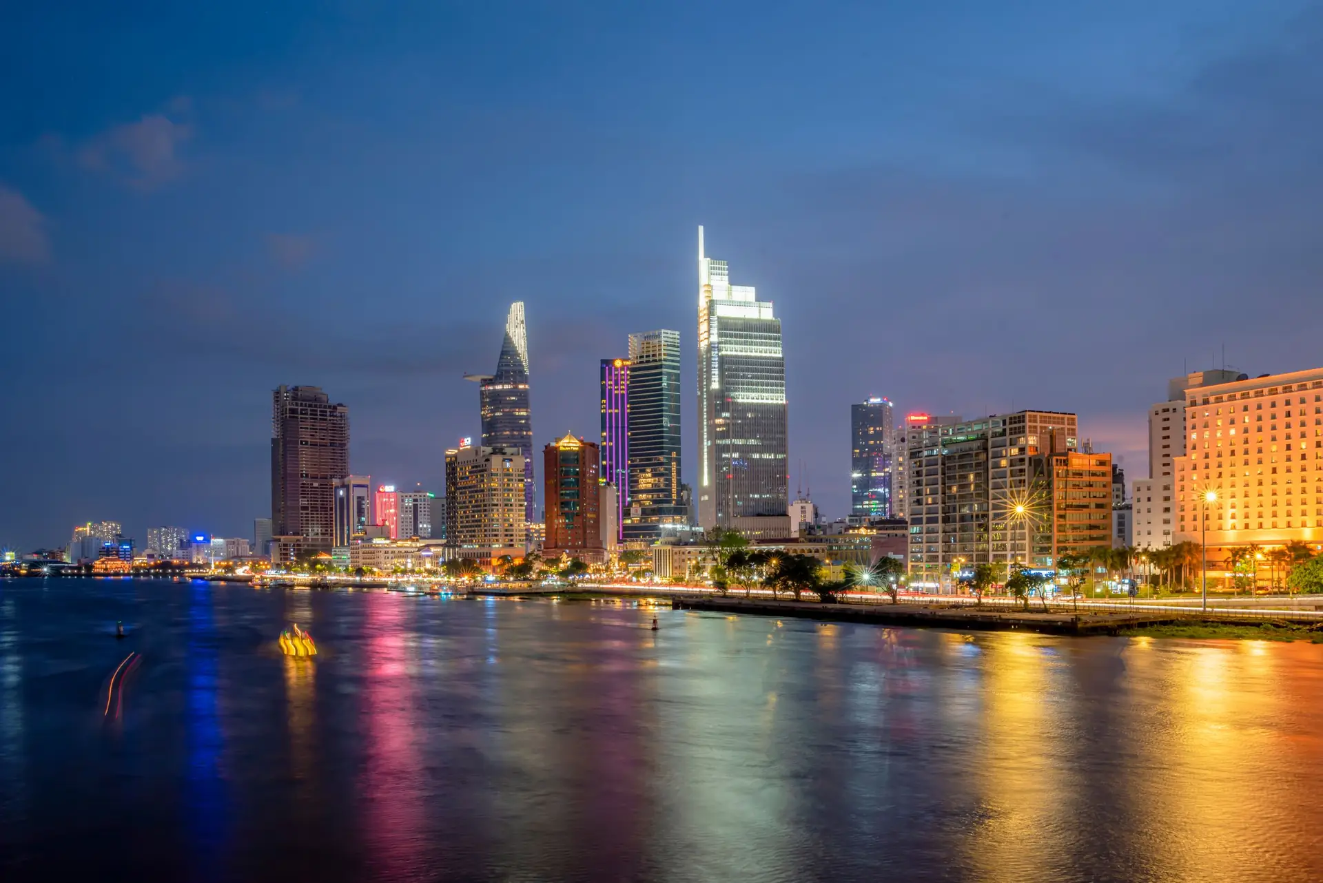 Stunning view of Ho Chi Minh City skyscrapers reflecting on the river at night.